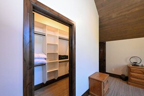 A walk-in closet with open shelves, a bed, and a wooden dresser. - Misty Mountain Lakefront Lodge with Dock and Hot Tub (Island Park)