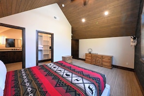 A bedroom with a bed, a wardrobe, a mirror, and a wall-mounted skull decoration. - Misty Mountain Lakefront Lodge with Dock and Hot Tub (Island Park)