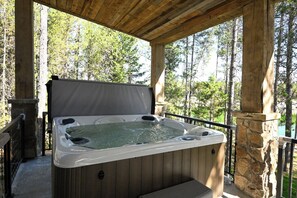 A hot tub in an outdoor wooden structure with a stone wall and a view of trees. - Misty Mountain Lakefront Lodge with Dock and Hot Tub (Island Park)