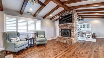 A living room with a fireplace, wooden beams, and a dining area.