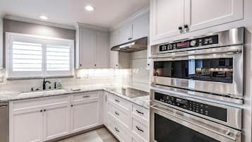 A modern kitchen with stainless steel appliances, white cabinetry, and a granite countertop.