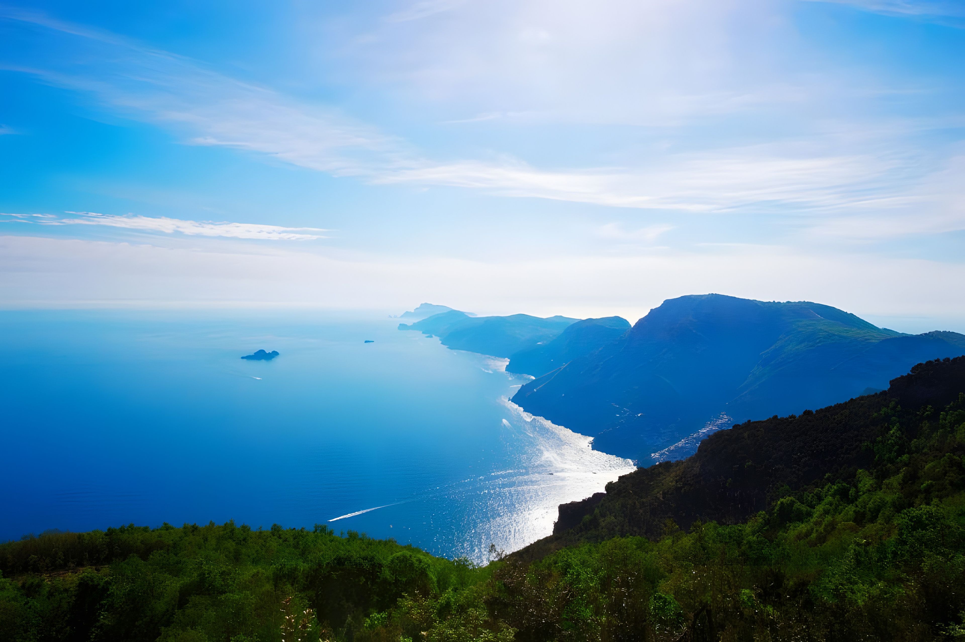 Eine Küstenlandschaft mit freiem Blick auf das Meer und ferne Berge.