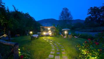 A garden with a stone pathway leading to a seating area with tables and chairs.
