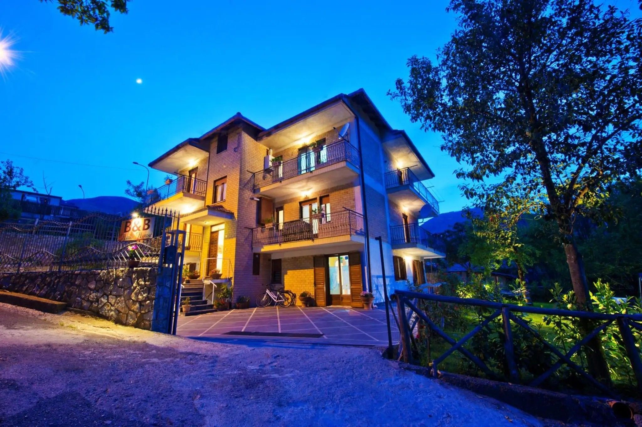 A multi-story hotel with a well-lit entrance and a gated driveway.