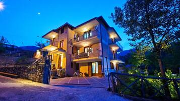 A multi-story hotel with a well-lit entrance and a gated driveway.