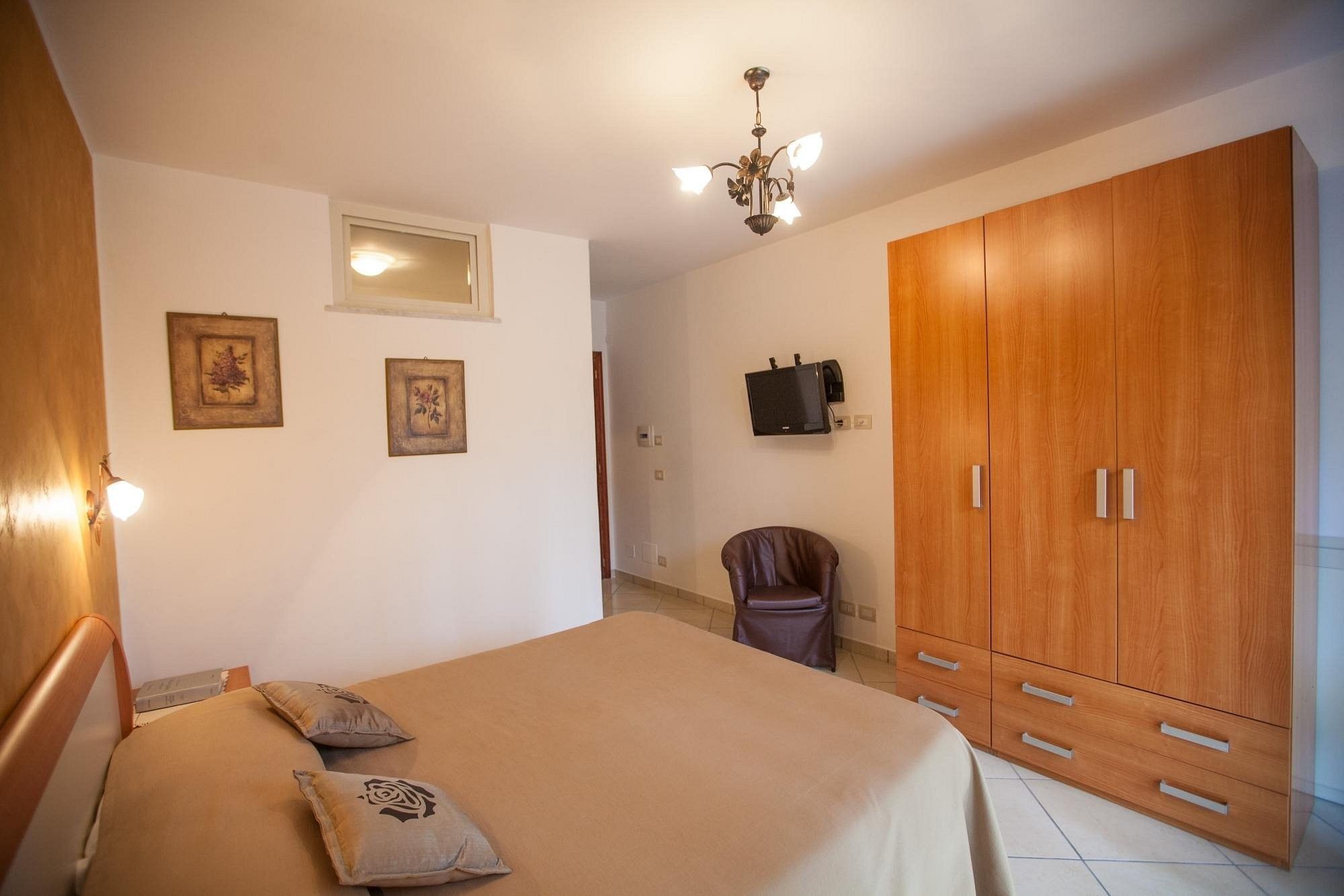 Ein Schlafzimmer mit Bett, Kleiderschrank, Fernseher und einer Kandelaber.