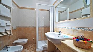 Ein Badezimmer mit Dusche, Toilette, Bidet und Waschbecken.
