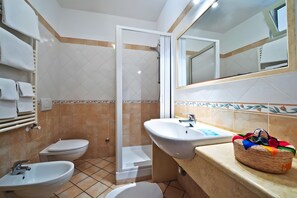 Une salle de bain équipée d’une douche, de toilettes, d’un bidet et d’un lavabo.