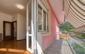 Ein Korridor mit einer Holztür, einem Fenster mit Jalousien und einem Balkon mit gestreiftem Markisenstoff.