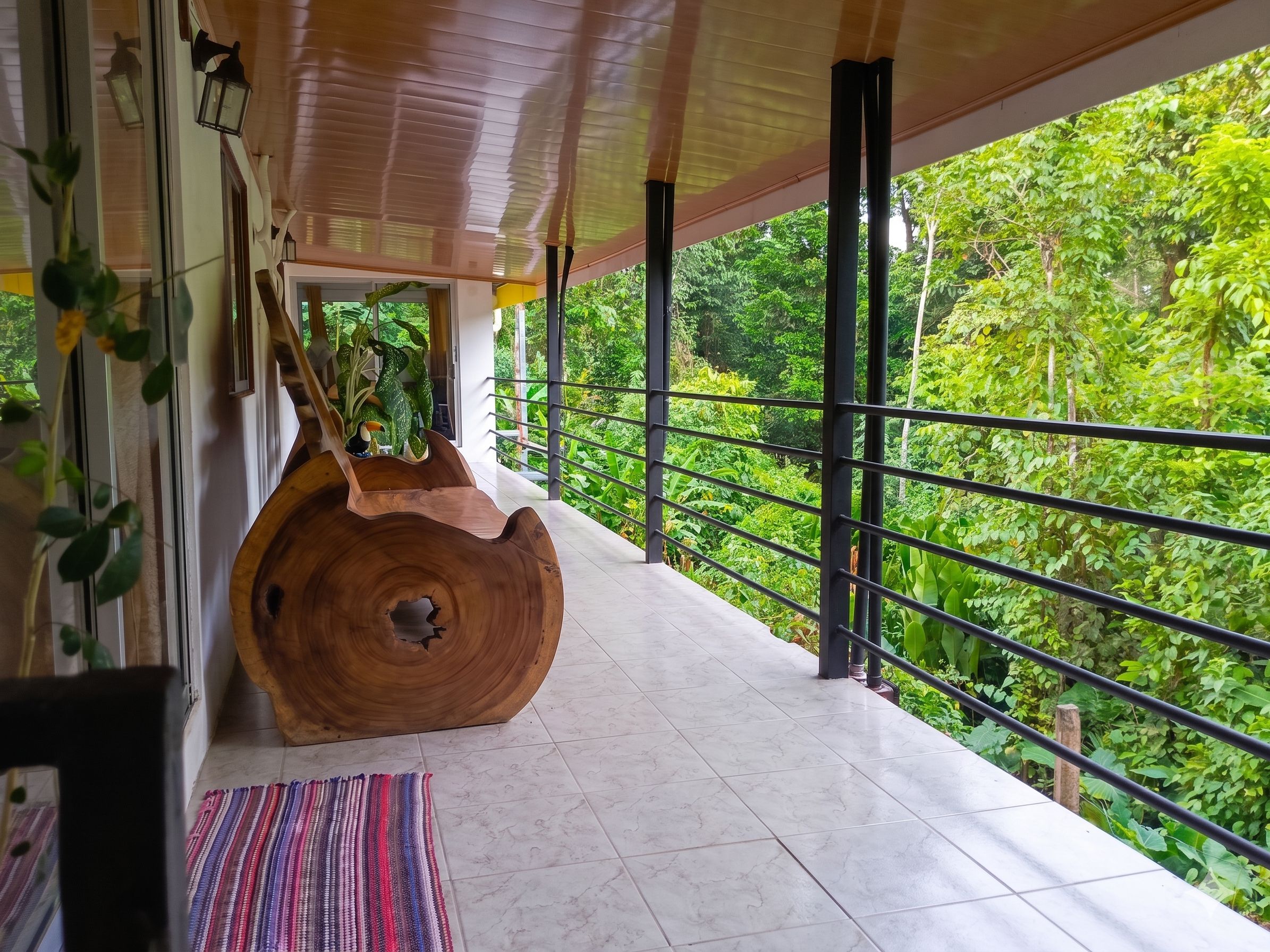 A wooden sculpture on a balcony with a view of dense greenery.