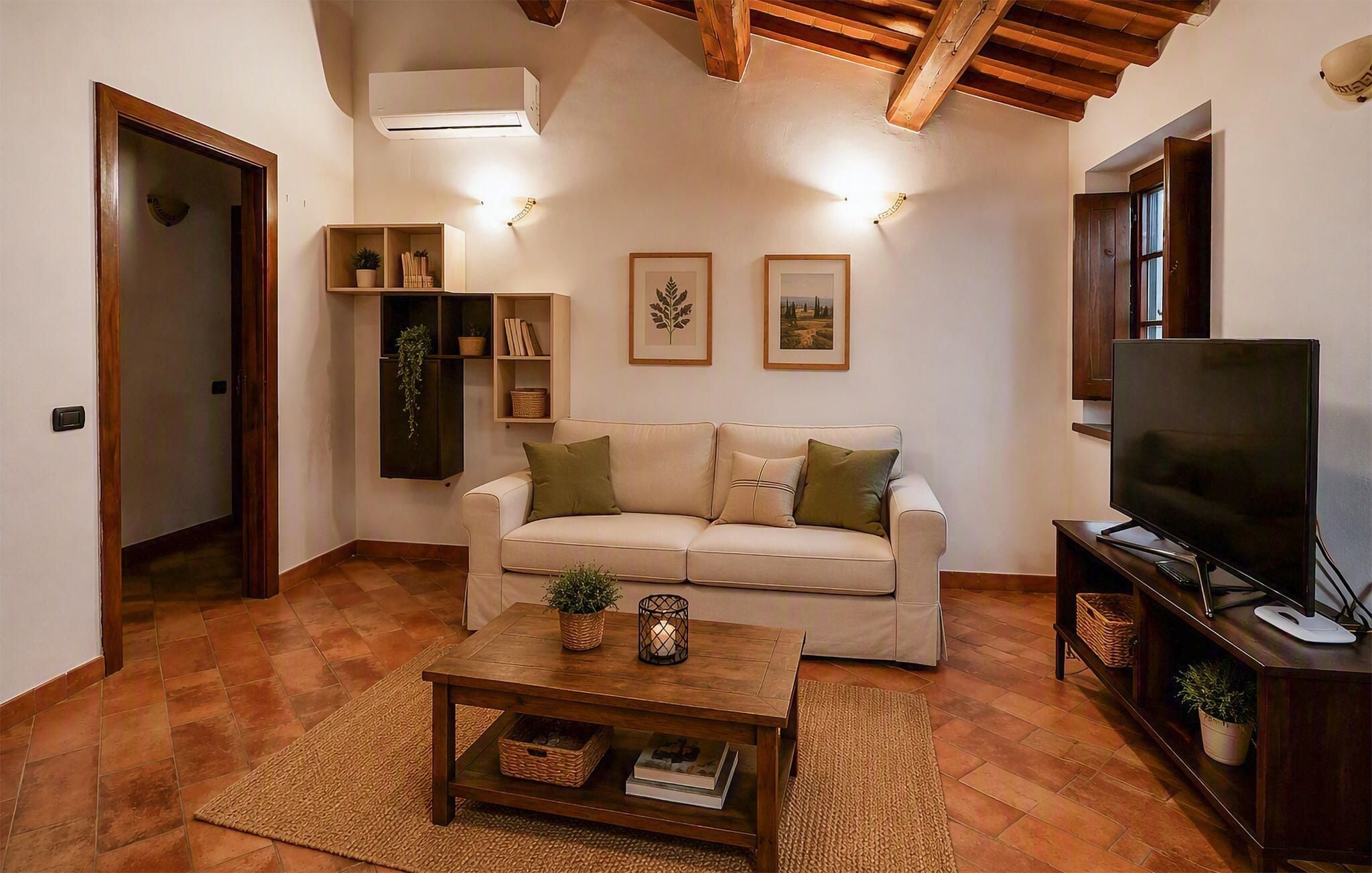 A living room with a sofa, a coffee table, a TV, and wall-mounted shelves with plants.