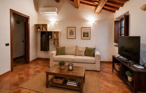 A living room with a sofa, a coffee table, a TV, and wall-mounted shelves with plants. - Amazing home in Appignano with WiFi (Appignano)