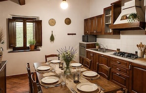 A kitchen with wooden cabinets, a stove, a microwave, and a dining table set for four. - Amazing home in Appignano with WiFi (Appignano)
