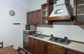 A kitchen with wooden cabinets, a built-in microwave, a gas stove, and a sink. - Amazing home in Appignano with WiFi (Appignano)