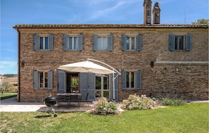 Un bâtiment à deux étages en briques, doté d’un patio aménagé avec du mobilier d’extérieur et un barbecue.