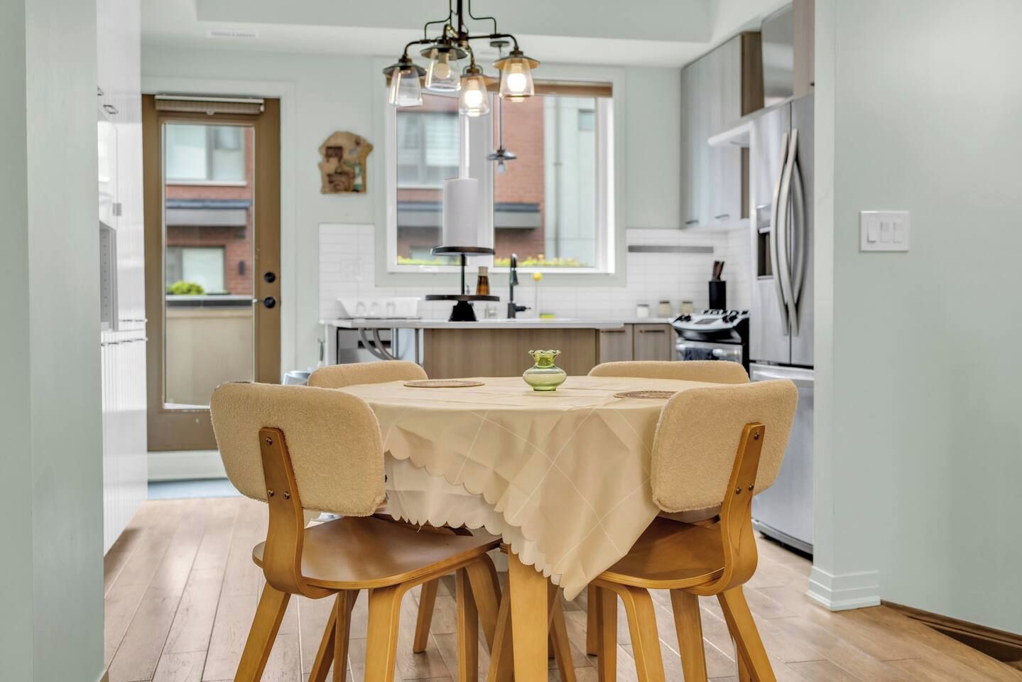 A dining area with a table set for four, surrounded by wooden chairs.