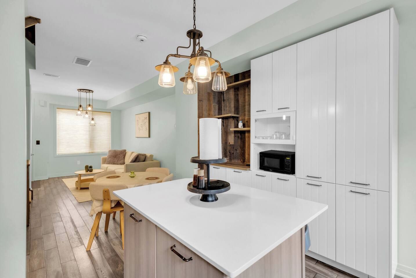 A modern kitchen with white cabinetry, a central island, and pendant lighting.