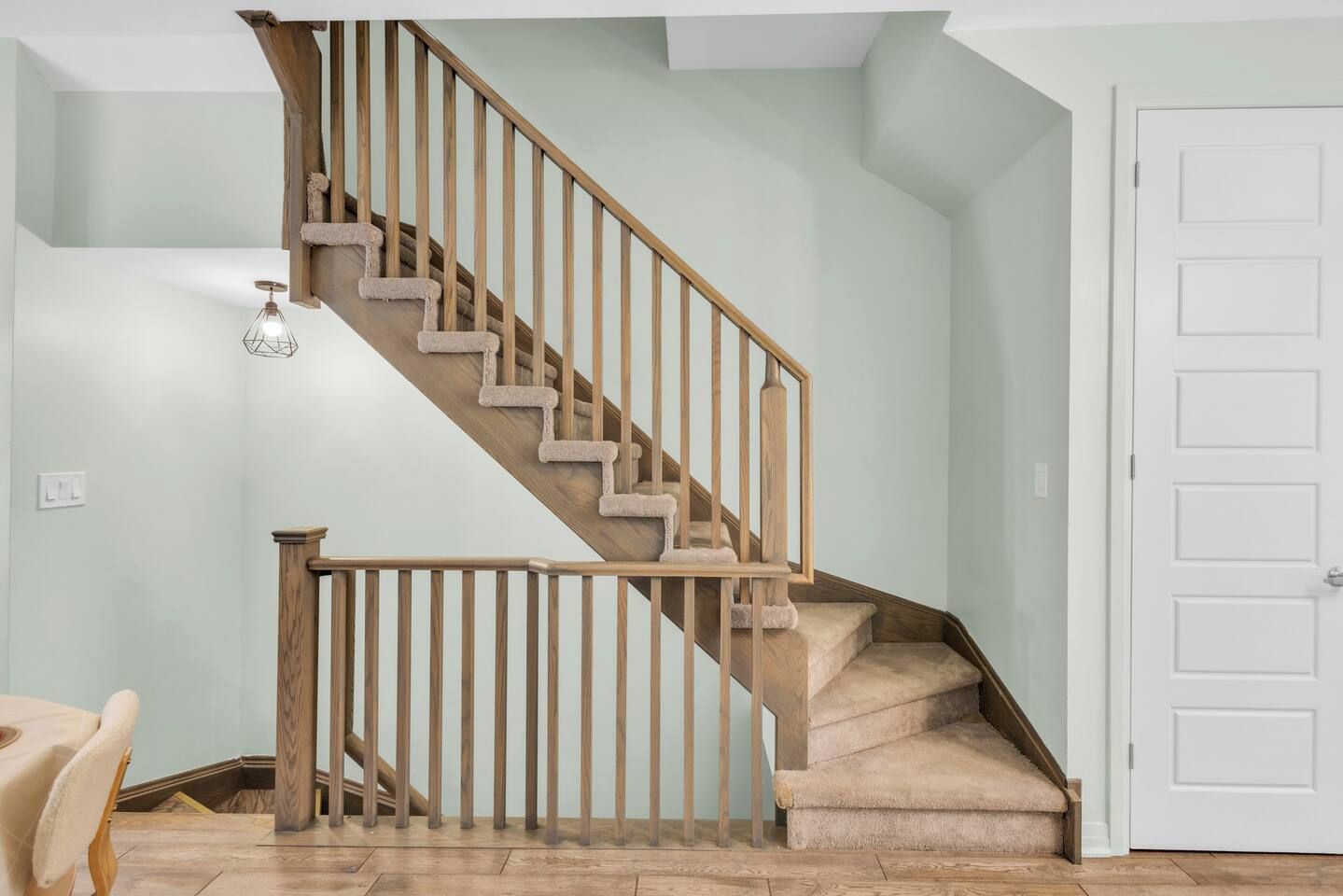 A staircase with wooden railings and carpeted steps leading to a door.