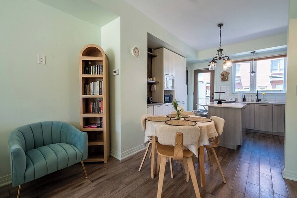 A modern kitchen with a dining area, wooden furniture, and a bookshelf.