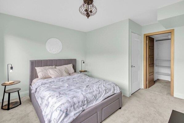 A bedroom with a bed, bedside tables, a wardrobe, and a door leading to a closet.
