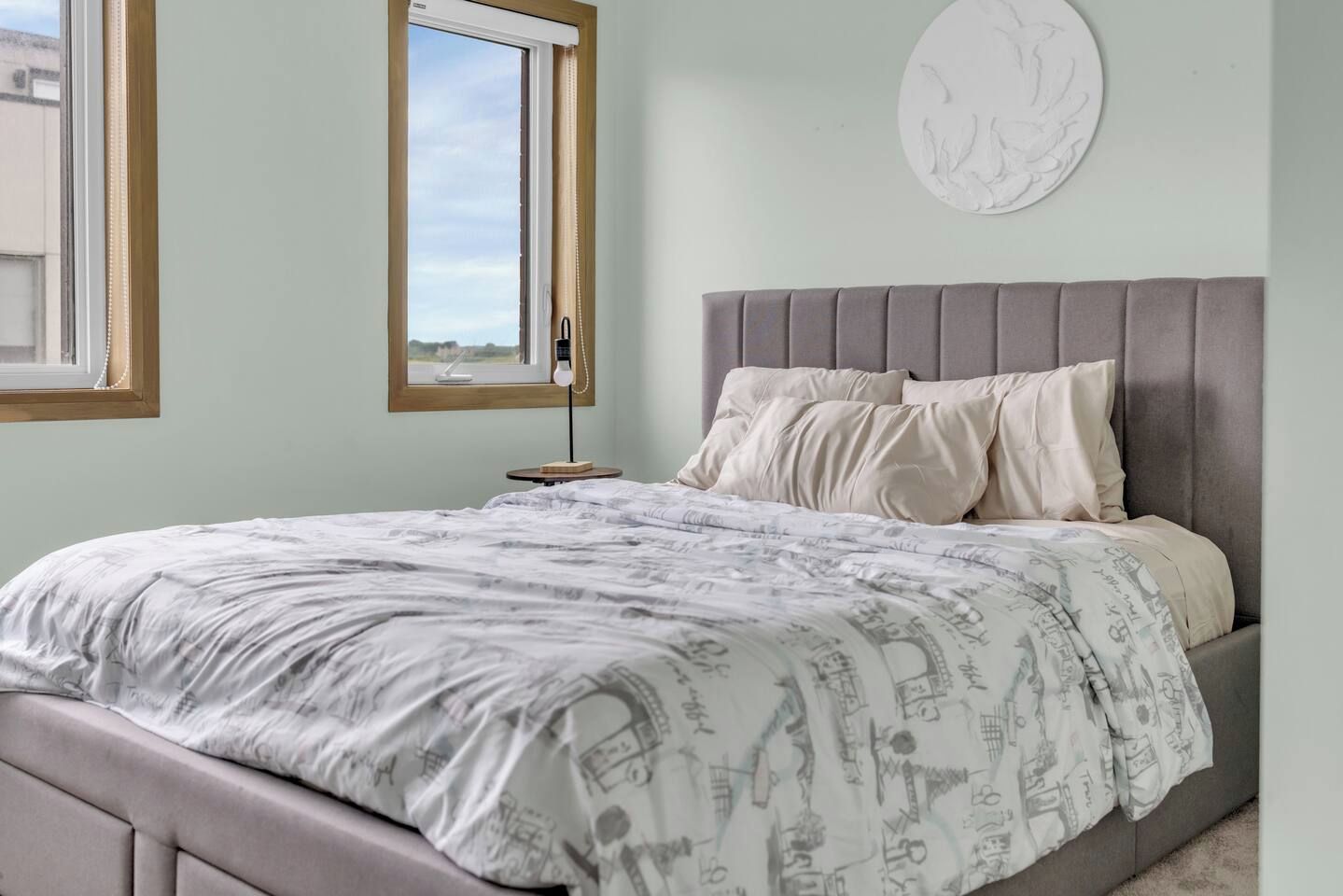 A bedroom with a bed, a nightstand, a lamp, and a window.
