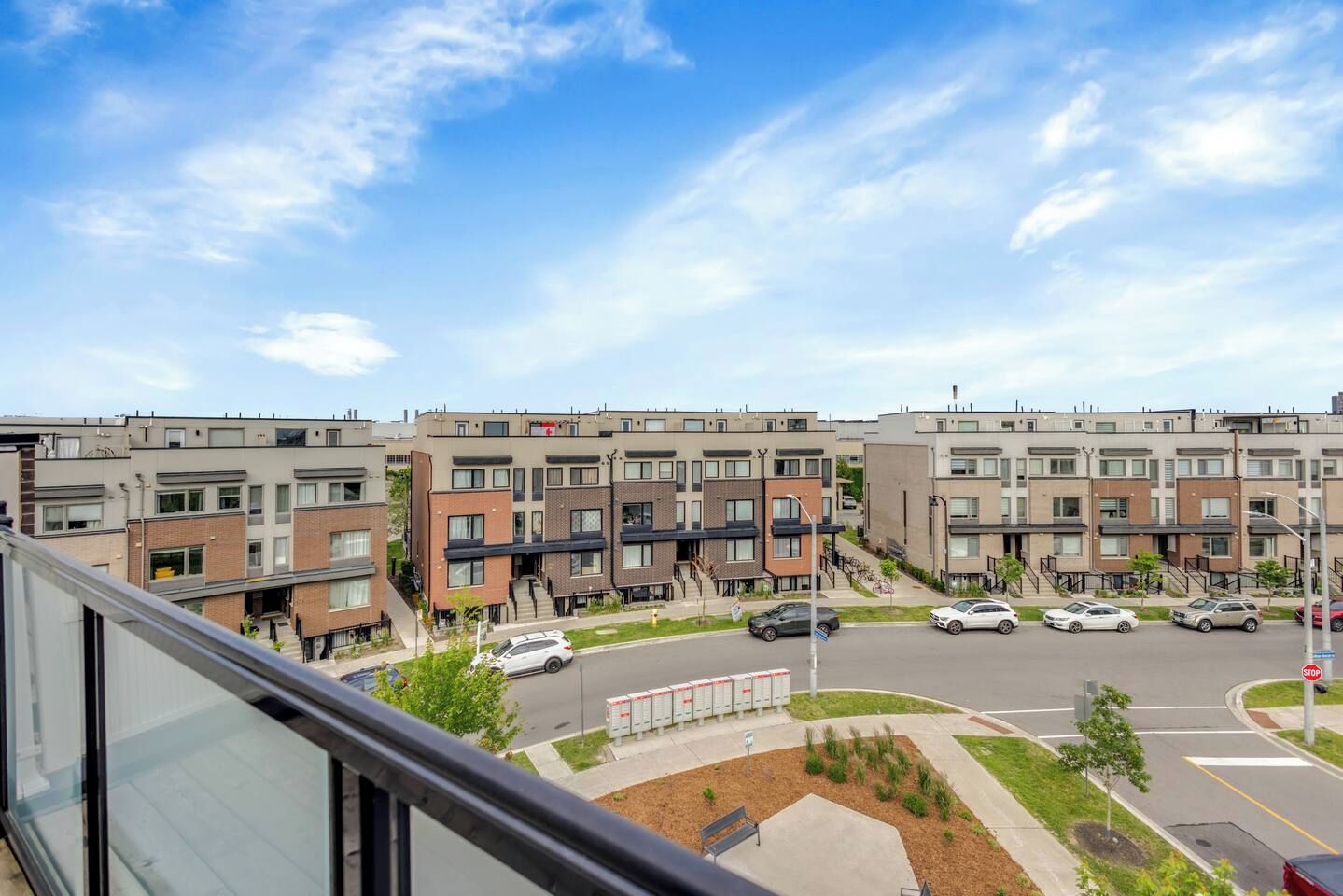 A residential area with modern apartment buildings, a parking lot, and a clear sky.