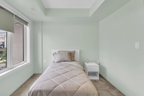 A bedroom with a bed, a nightstand, and a window. - Modern 4BR Townhome | Rooftop Terraces | Downsview (Toronto)