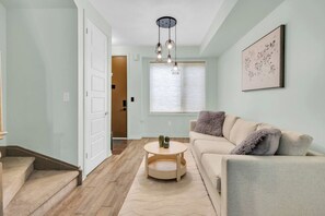A living room with a sofa, a coffee table, and a door leading to another room.