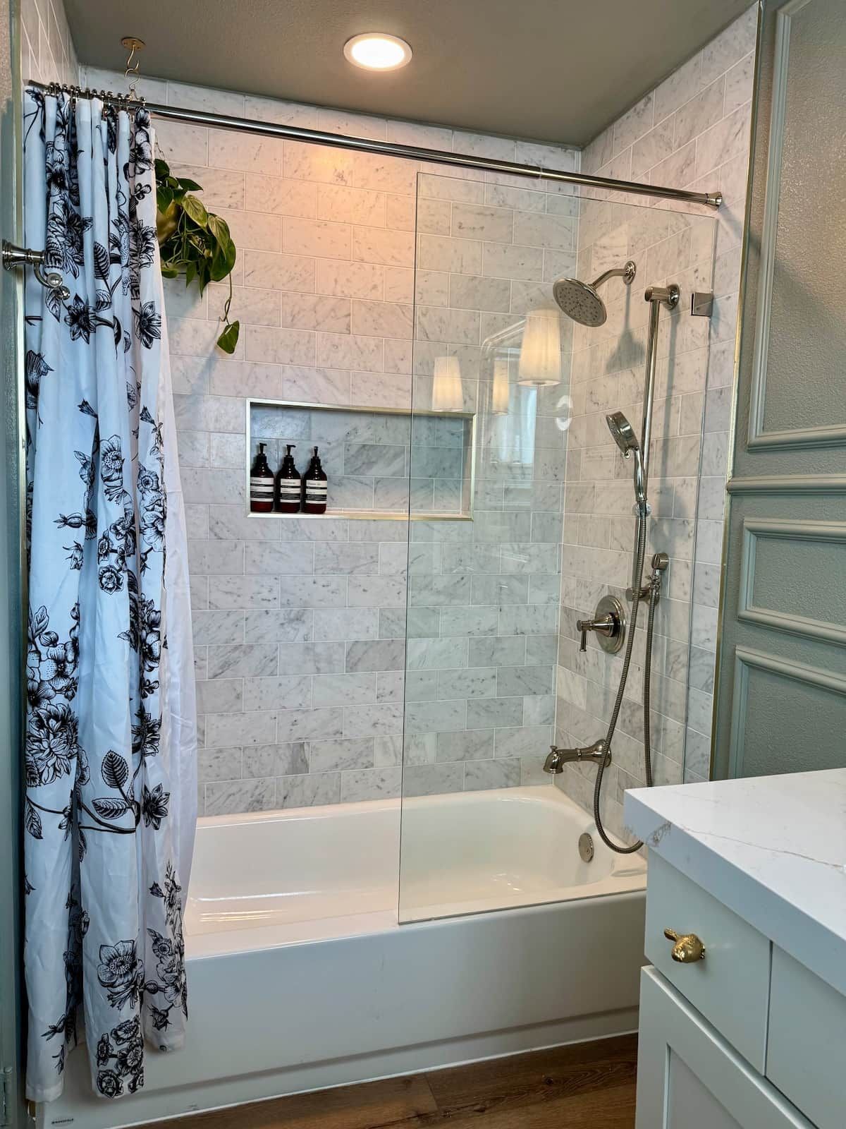 A bathroom with a glass shower enclosure, a bathtub, and a vanity with a mirror.