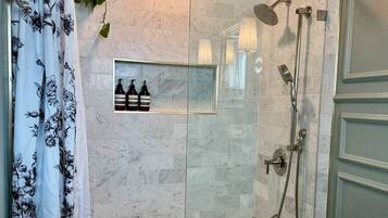 A bathroom with a glass shower enclosure, a bathtub, and a vanity with a mirror.