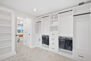 A walk-in closet with open doors, featuring shelves, drawers, and hanging space.