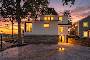 A modern two-story house with a stone facade, large windows, and a visible garage entrance.