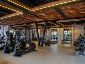 Et fitnessrum med forskellig træningsudstyr, trælofter og store vinduer.