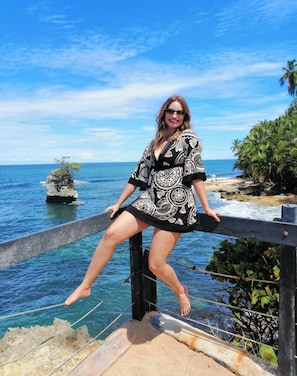 A person standing on a balcony overlooking a coastal area with clear blue water and a rocky outcrop. - Apartamentos y Villas D Angelo - Superior Apartment 101 (Manzanillo)