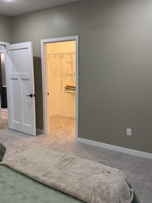 A room with a bed, a door, and a closet with hanging clothes.