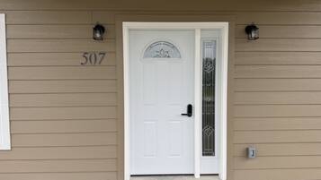 A beige house with a white door, number 507, and two wall-mounted lanterns.