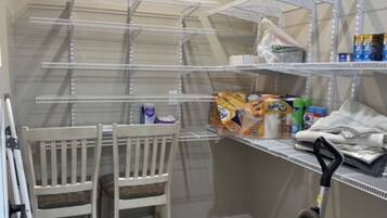 A storage closet with metal shelving, a chair, and a vacuum cleaner.