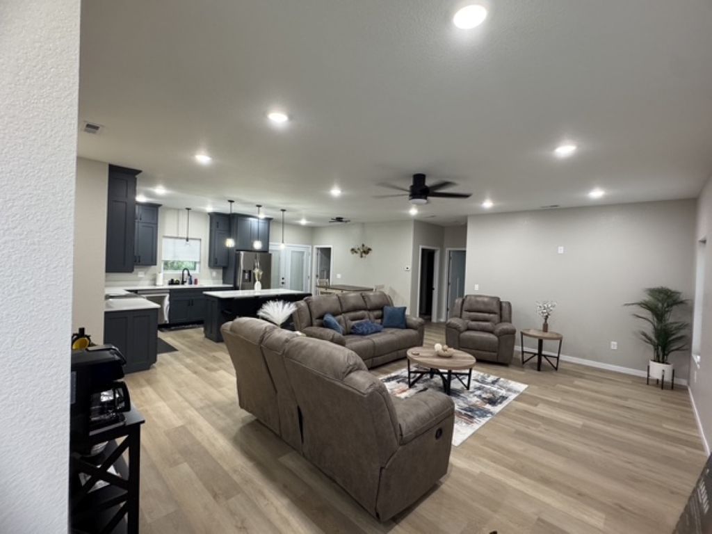 A modern living room with a sectional sofa, a coffee table, and a dining area with a kitchen in the background.