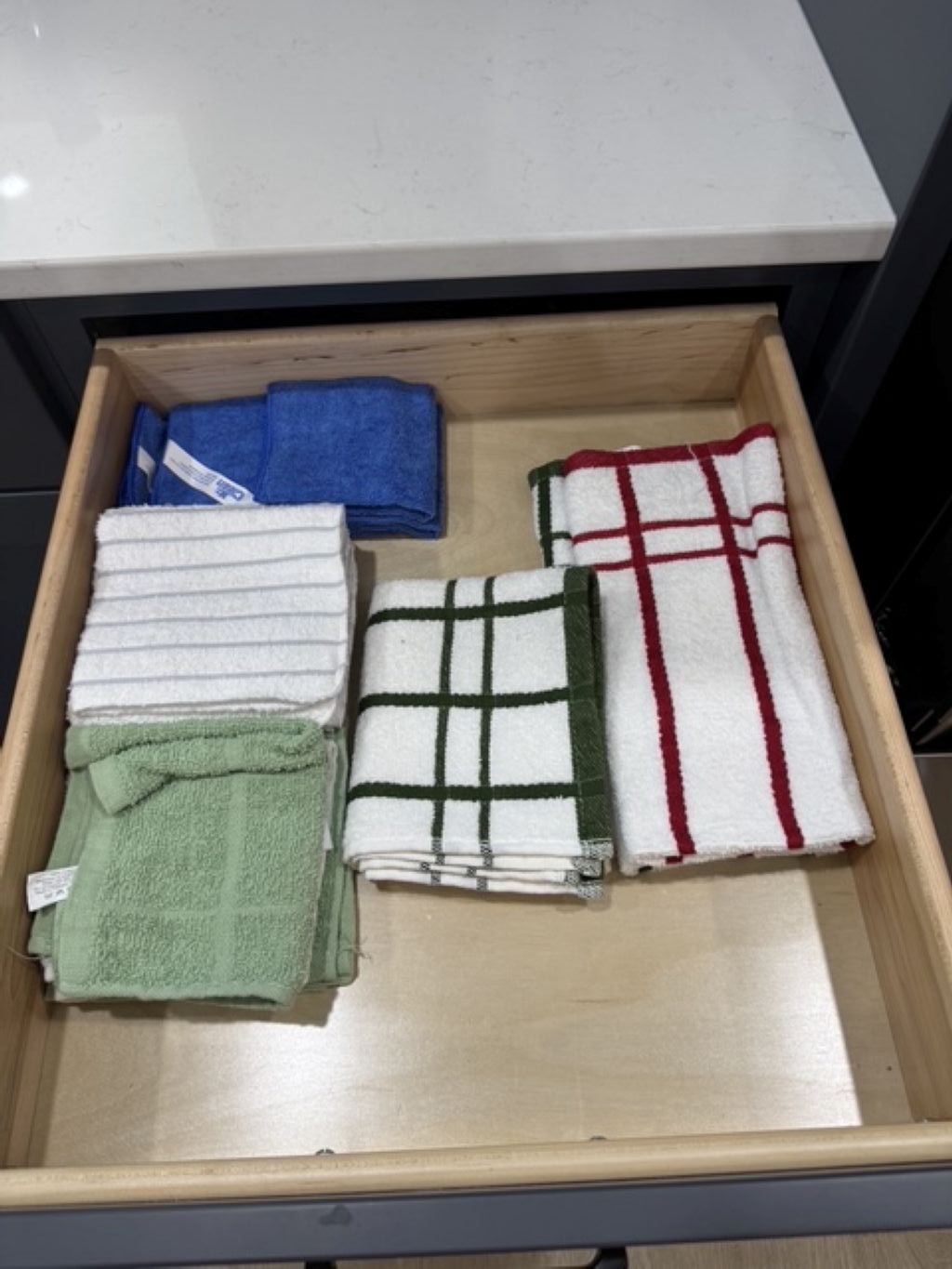 A drawer with folded towels in various colors.