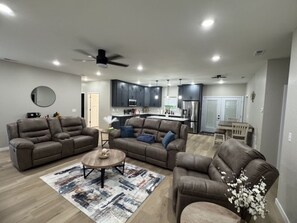 A modern living room with a sectional sofa, a coffee table, and a dining area in the background.