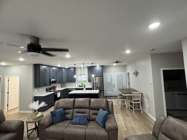 Una sala de estar moderna con un sofá, una mesa de comedor y una cocina al fondo.