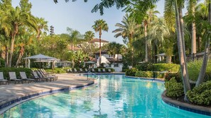 Una piscina rodeada de palmeras y sillas de descanso.