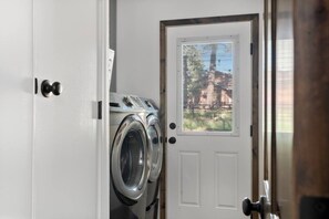 A laundry room with a front door, a window with blinds, and a washing machine. - Hot tub - Fireplace - Game Room (Flagstaff)