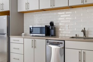 A kitchen with white cabinets, a stainless steel dishwasher, a microwave, and a coffee maker on the countertop. - Hot tub - Fireplace - Game Room (Flagstaff)