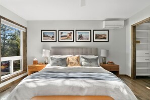 A modern bedroom with a large bed, bedside tables, a wardrobe, and a window with a view. - Hot tub - Fireplace - Game Room (Flagstaff)