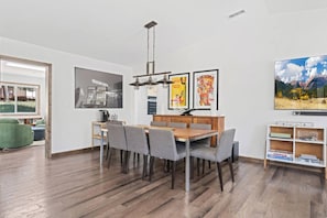 A modern dining area with a wooden table and chairs, a hanging light fixture, and framed artwork on the walls. - Hot tub - Fireplace - Game Room (Flagstaff)