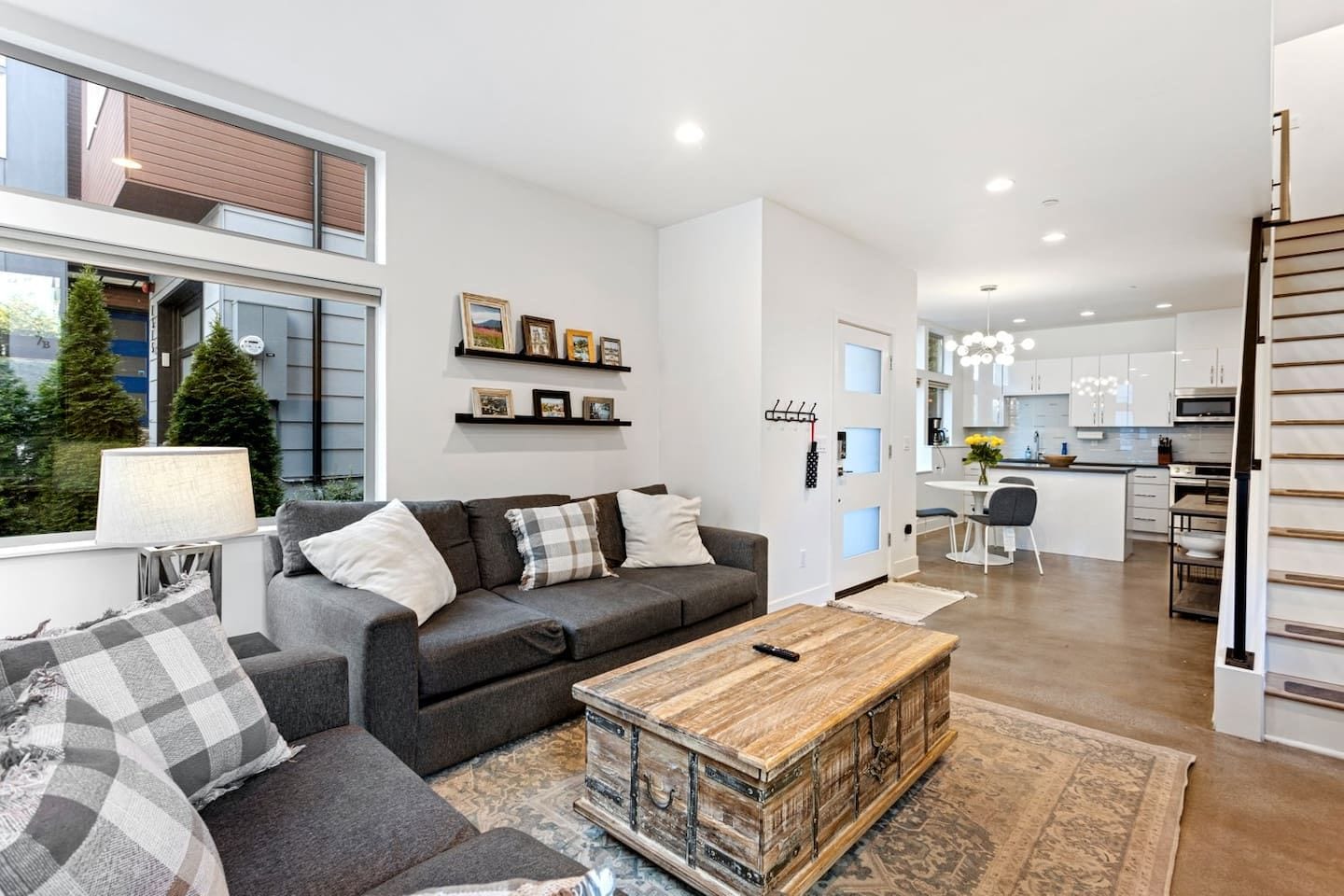 A modern living room with a sofa, coffee table, and a view of the kitchen.