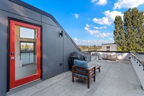 A rooftop terrace with a red door, a covered grill, and a seating area. - Modern 3 br townhouse near downtown (Seattle)