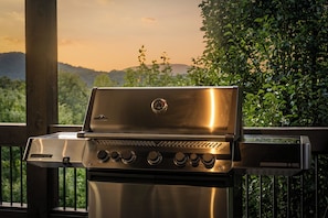 Ein Edelstahl-Grill für den Außenbereich mit digitalem Thermometer, auf einem Balkon mit Blick auf Grünflächen und Berge.