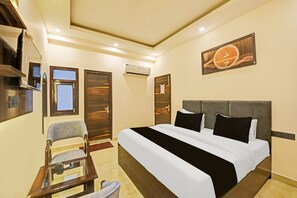 A hotel room with a bed, a chair, a desk, and a painting on the wall. - Classic Charmwood Inn (Faridabad)